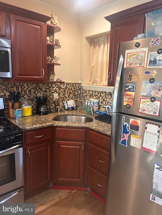 kitchen with stone countertops, sink, appliances with stainless steel finishes, and light hardwood / wood-style floors