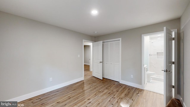 unfurnished bedroom with a closet, light hardwood / wood-style floors, and ensuite bath