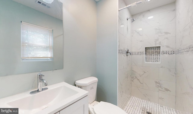 bathroom featuring tiled shower, vanity, and toilet