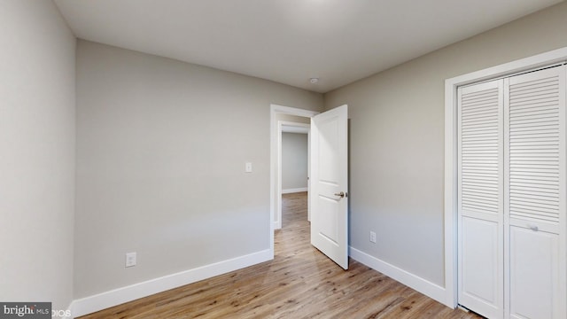 unfurnished bedroom featuring light hardwood / wood-style flooring and a closet