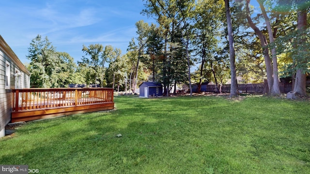 view of yard featuring a wooden deck and a storage shed