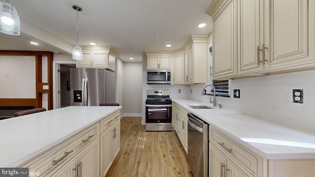 kitchen with cream cabinetry, decorative light fixtures, sink, and stainless steel appliances