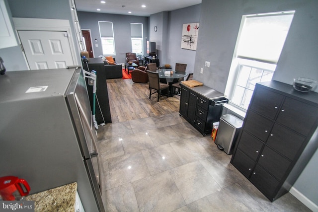 kitchen with light wood-type flooring, a healthy amount of sunlight, and stainless steel fridge