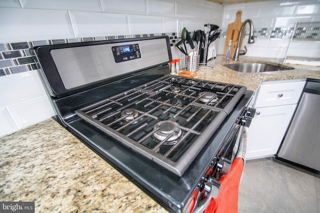 room details featuring light stone counters, sink, white cabinetry, stainless steel appliances, and decorative backsplash