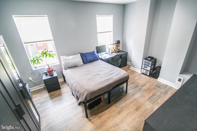 bedroom with multiple windows and light wood-type flooring