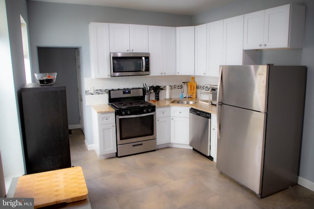 kitchen featuring light stone counters, white cabinets, sink, tasteful backsplash, and stainless steel appliances