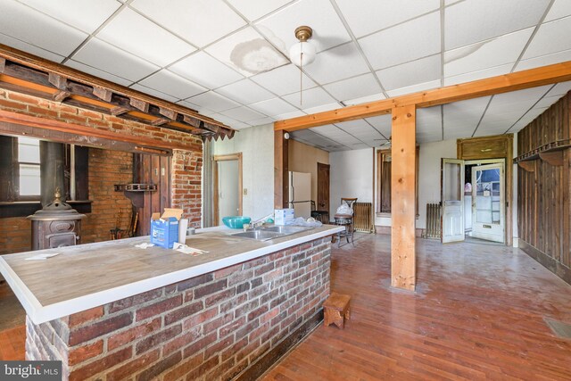 kitchen with a paneled ceiling, hardwood / wood-style floors, a wood stove, and white refrigerator