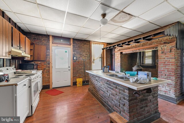 kitchen featuring a breakfast bar, hardwood / wood-style flooring, sink, electric stove, and a drop ceiling