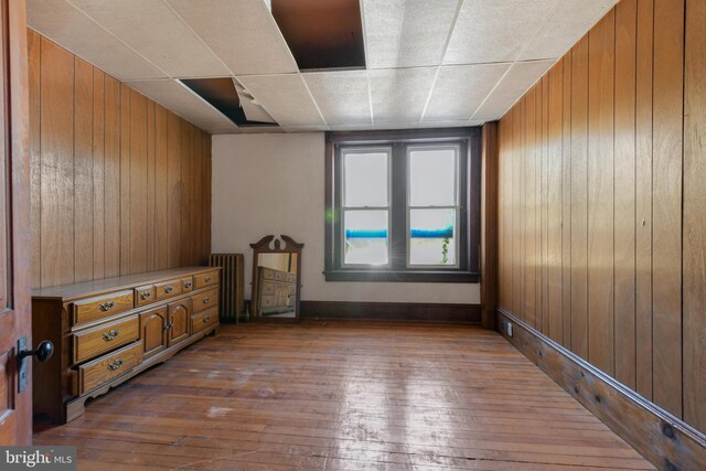 unfurnished bedroom with wood-type flooring, radiator, and wooden walls