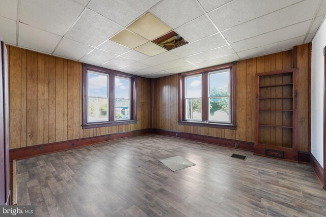 spare room featuring hardwood / wood-style flooring, wooden walls, and a paneled ceiling