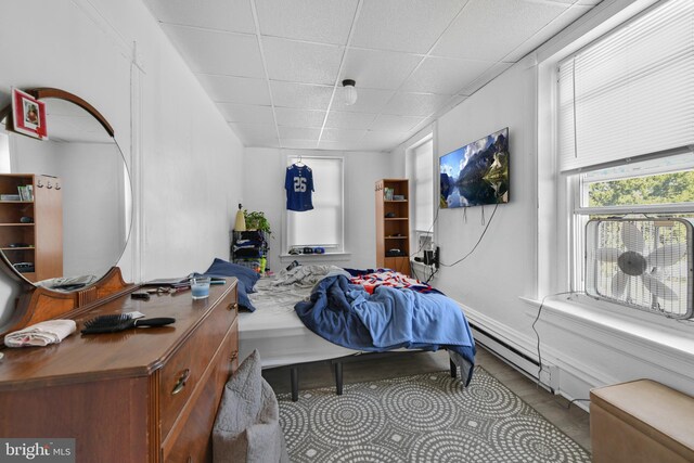 bedroom featuring a paneled ceiling and a baseboard heating unit