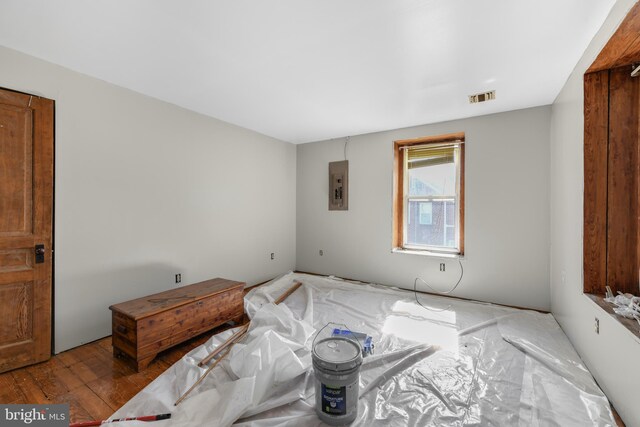 bedroom with electric panel and hardwood / wood-style flooring