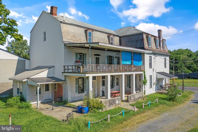 back of house featuring a balcony and a yard