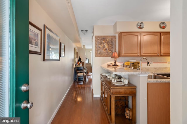 kitchen with dark hardwood / wood-style flooring, light stone counters, sink, and a kitchen breakfast bar