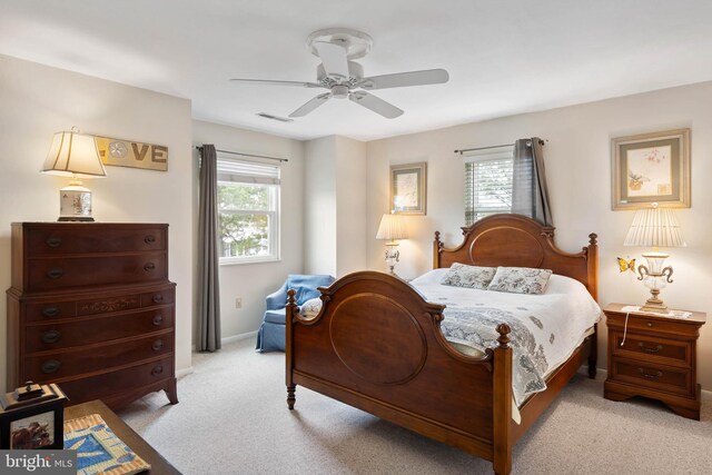 bedroom featuring baseboards, multiple windows, visible vents, and light colored carpet