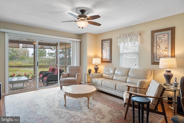 living area with a textured ceiling, wood finished floors, and a ceiling fan