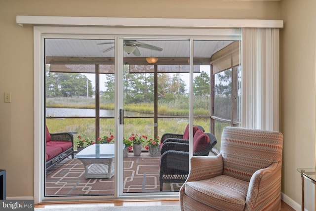 sunroom / solarium with ceiling fan and a water view