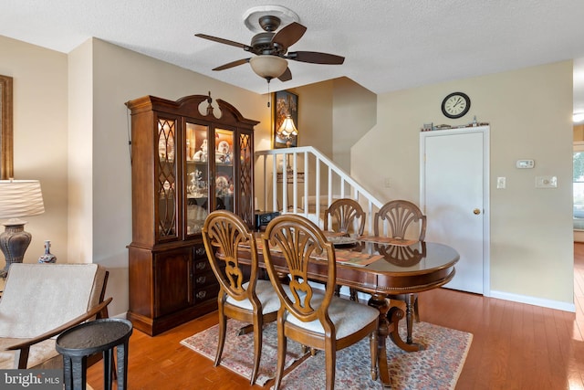 dining room with a textured ceiling, ceiling fan, and hardwood / wood-style floors