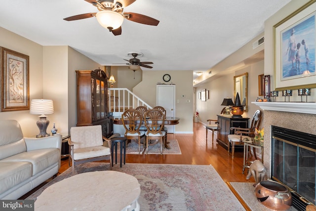 living area featuring baseboards, visible vents, a fireplace with flush hearth, stairway, and wood finished floors