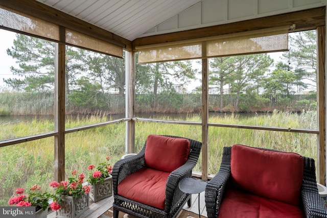 sunroom featuring lofted ceiling, a healthy amount of sunlight, and a water view