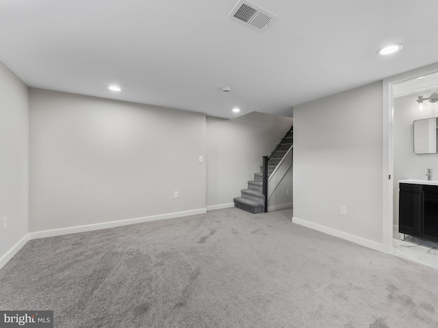 basement featuring light colored carpet and sink