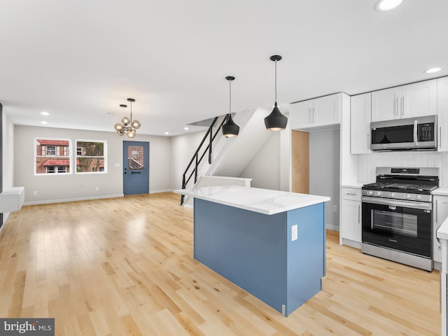 kitchen with light wood-type flooring, light stone countertops, stainless steel appliances, a chandelier, and white cabinetry