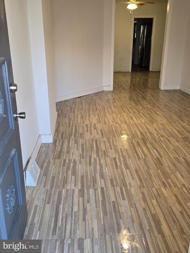 empty room featuring visible vents, baseboards, ceiling fan, and wood finished floors