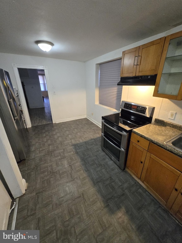 kitchen with under cabinet range hood, a textured ceiling, appliances with stainless steel finishes, and brown cabinetry