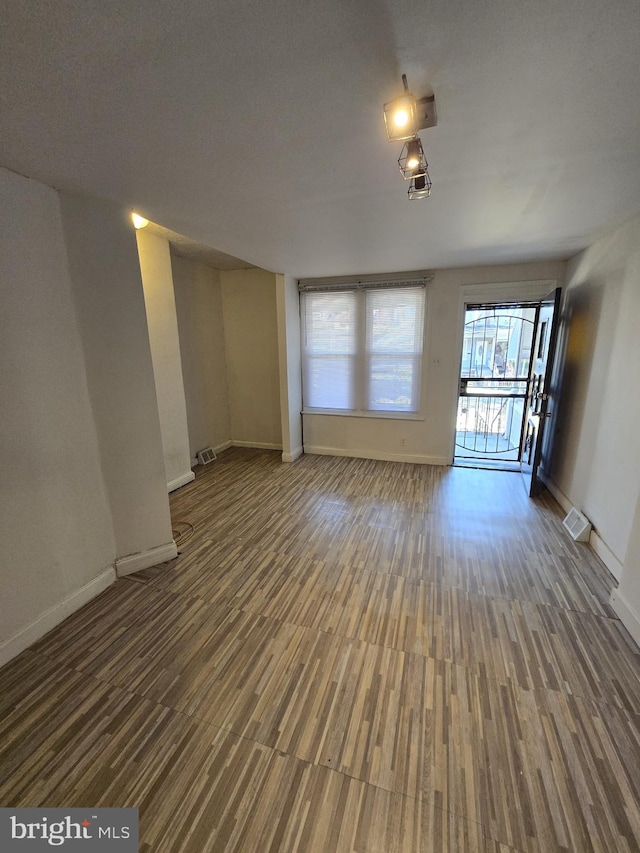 unfurnished living room with visible vents, baseboards, and wood finished floors