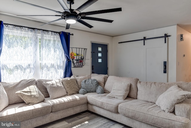 living room featuring wood-type flooring, ceiling fan, and a barn door