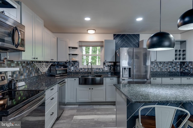 kitchen featuring pendant lighting, stainless steel appliances, light hardwood / wood-style floors, and white cabinets