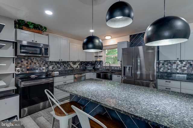 kitchen with sink, backsplash, appliances with stainless steel finishes, a kitchen breakfast bar, and light hardwood / wood-style floors