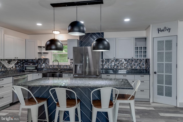 kitchen with pendant lighting, sink, tasteful backsplash, appliances with stainless steel finishes, and a center island