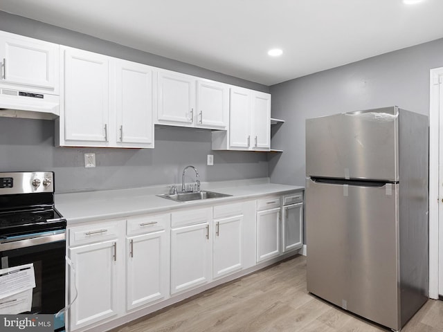 kitchen with light wood-style flooring, appliances with stainless steel finishes, white cabinets, a sink, and under cabinet range hood