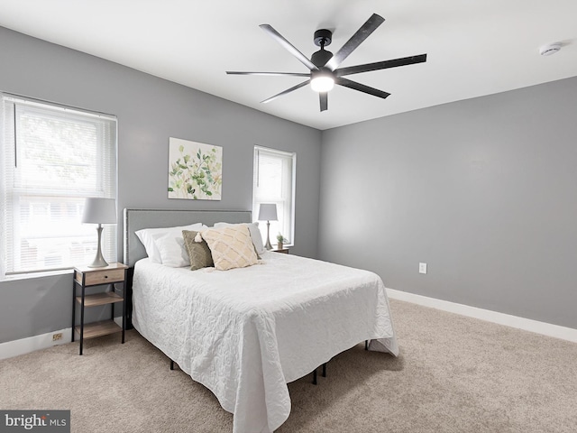 bedroom with light colored carpet, ceiling fan, and baseboards