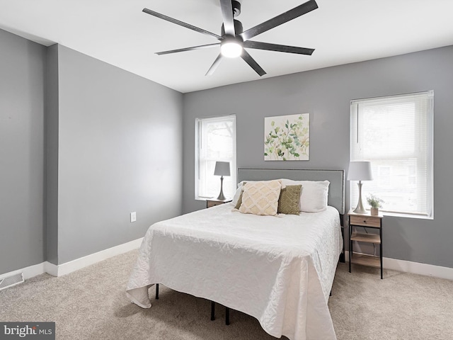 bedroom with baseboards, ceiling fan, visible vents, and light colored carpet