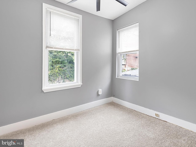 carpeted empty room with ceiling fan and baseboards