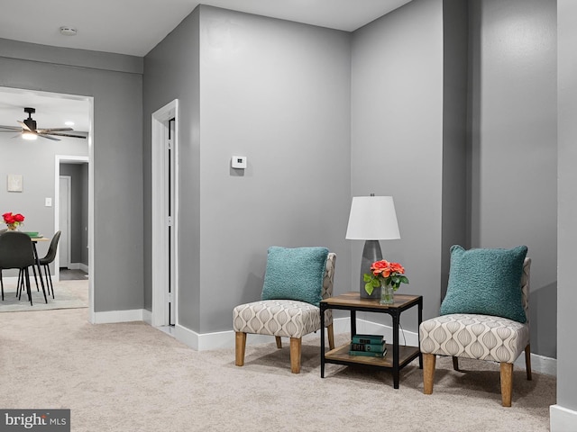 sitting room featuring a ceiling fan, light carpet, and baseboards