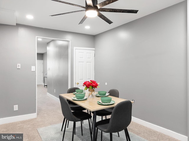 dining space with light carpet, ceiling fan, and baseboards