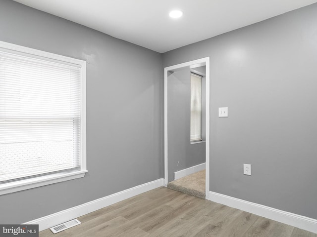 spare room featuring light wood-style floors, visible vents, and baseboards