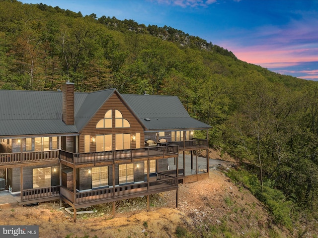 back house at dusk with a wooden deck and central air condition unit