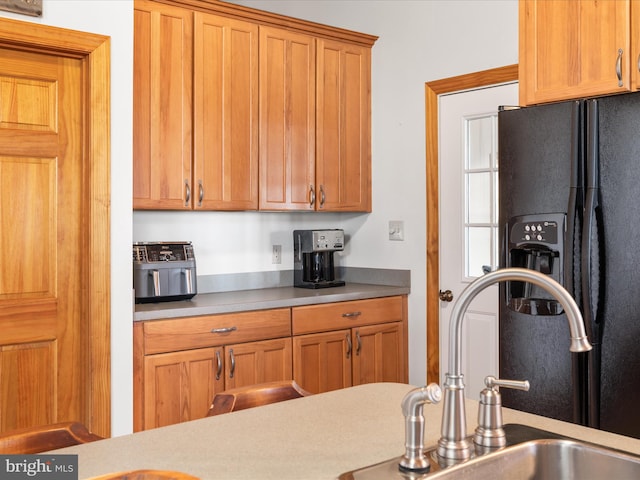 kitchen featuring black refrigerator with ice dispenser and sink