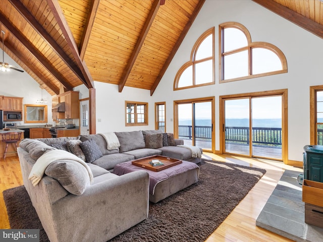 living room featuring light wood-type flooring, a water view, and high vaulted ceiling