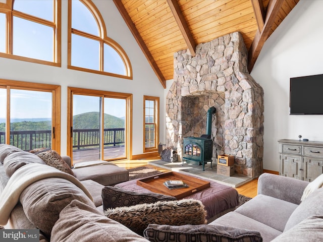 living room featuring light hardwood / wood-style floors, high vaulted ceiling, a mountain view, a wood stove, and wooden ceiling