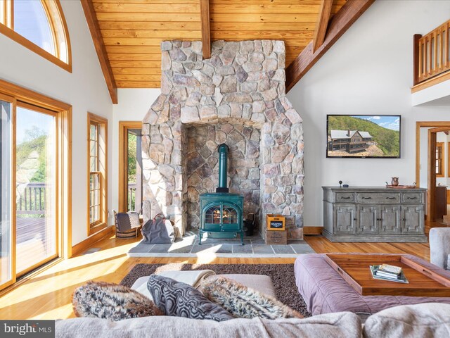 living room with wood-type flooring, beamed ceiling, a wood stove, high vaulted ceiling, and wooden ceiling