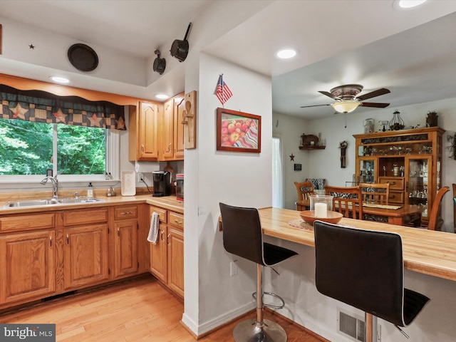 kitchen featuring wooden counters, ceiling fan, light hardwood / wood-style floors, and sink