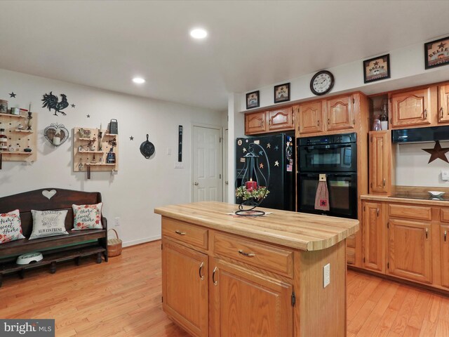 kitchen with exhaust hood, butcher block countertops, black appliances, light hardwood / wood-style flooring, and a center island