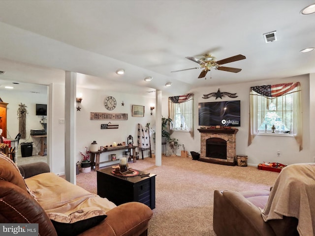 carpeted living room featuring ceiling fan and a stone fireplace