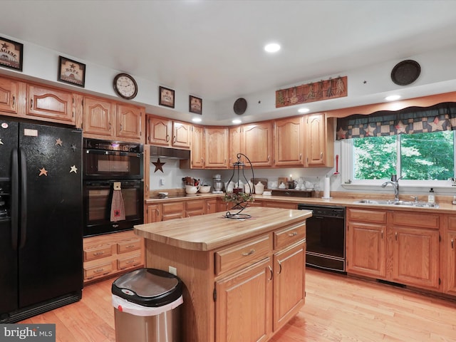 kitchen featuring black appliances, wood counters, light hardwood / wood-style floors, a center island, and sink