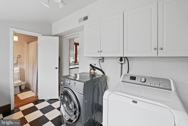 clothes washing area with cabinets and washer and clothes dryer